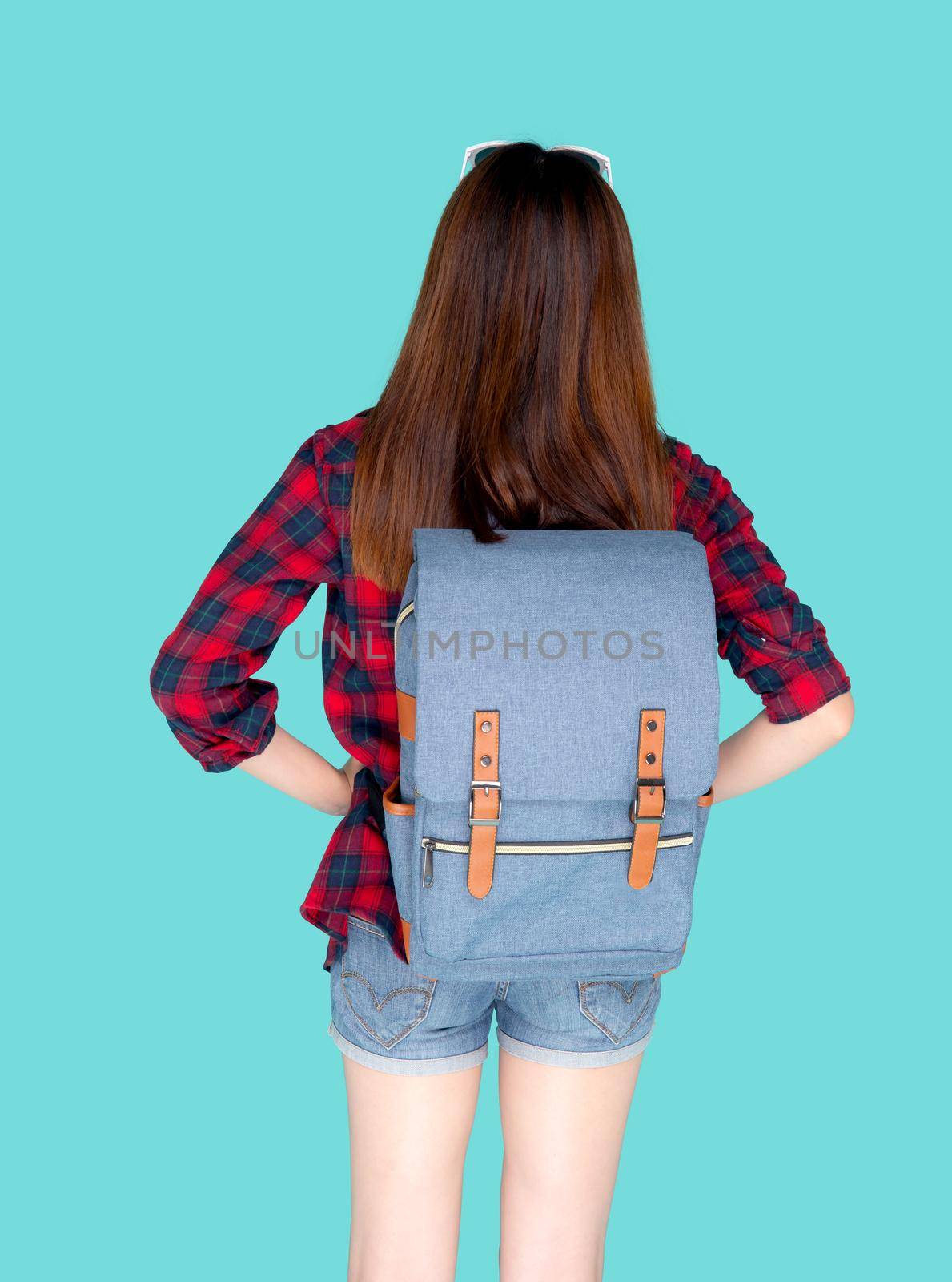 Back view of beautiful young asian woman travel with backpack isolated on blue background, rear asia girl is student or tourist in vacation in summer trip, holiday and traveller concept. by nnudoo