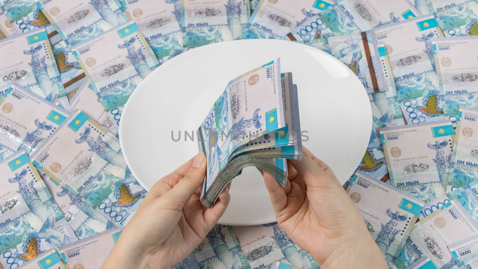 Count money in tenge. A lot of Kazakhstani tenge on a white plate. The national currency of Kazakhstan. Salary in tenge. To cut the budget.