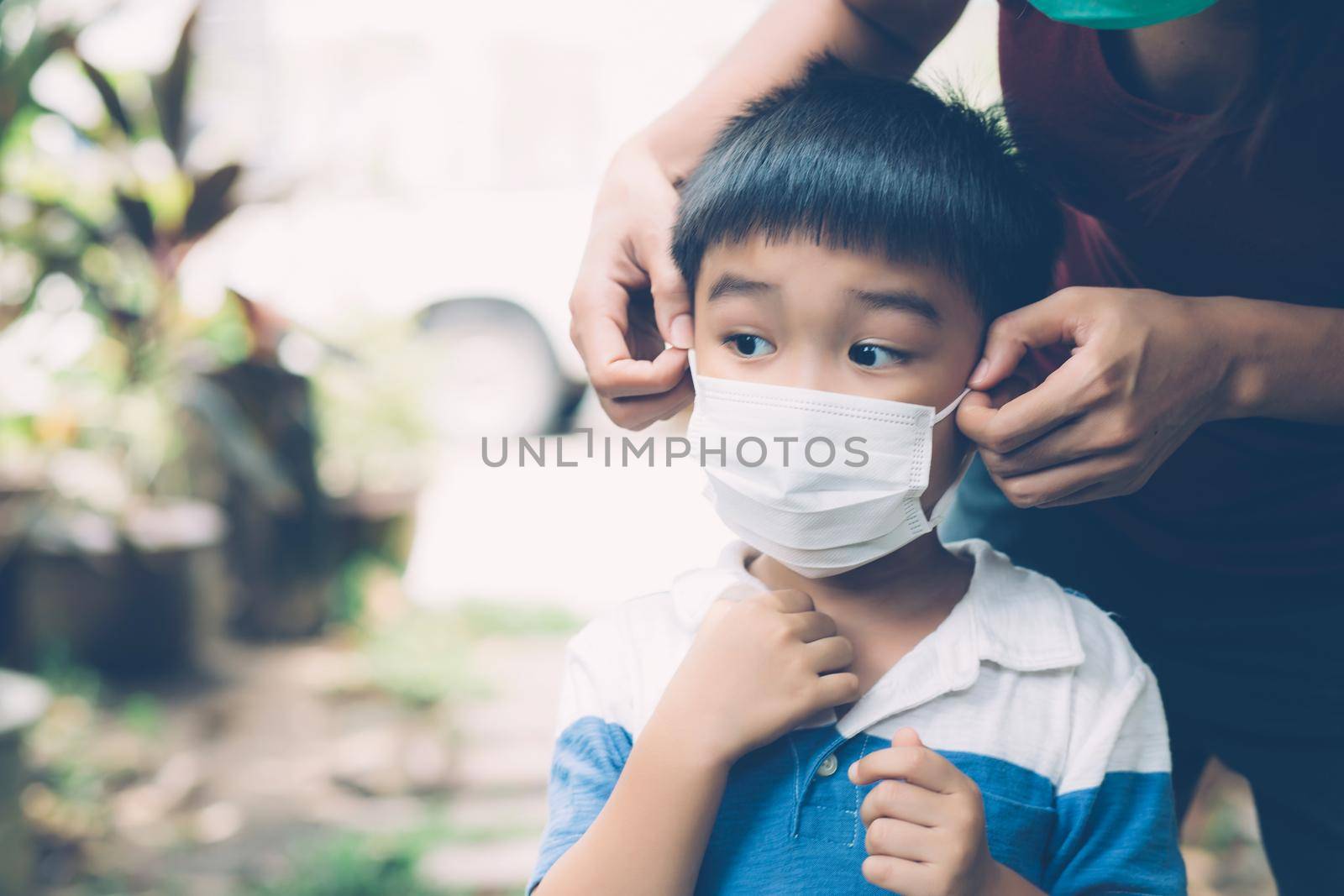 Mother take care son with face mask for protection disease flu or covid-19 outdoors, mom wearing on medical mask with child safety for protect outbreak of pandemic in public, medical concept. by nnudoo