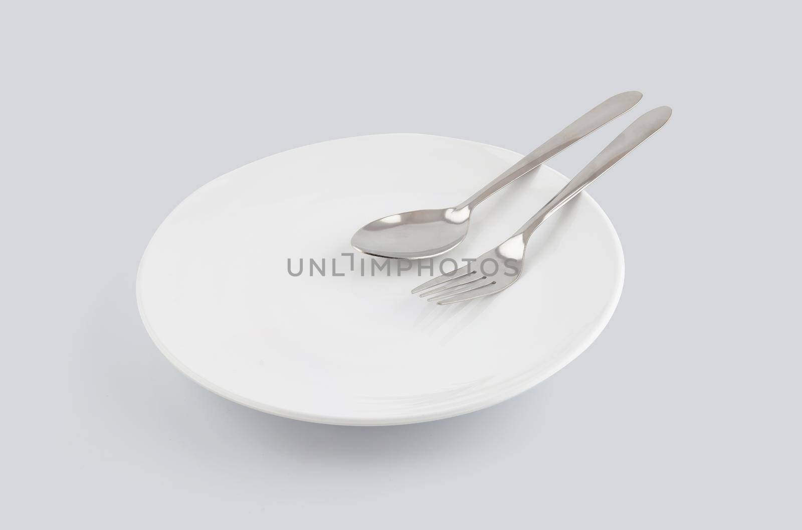 Dish spoon and fork isolated on white background, utensil for food, ceramic plate with empty, kitchenware or dishware with stainless in studio, object concept.