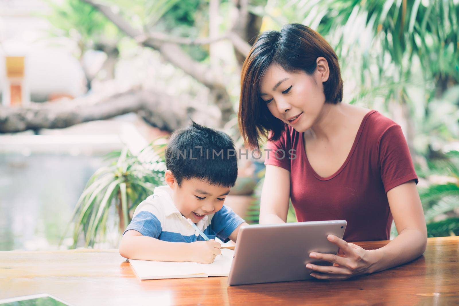 Son using digital tablet computer for study and learn to internet online with mother together, education from home, family recreation, mom teach boy and homework with technology, lifestyle concept. by nnudoo
