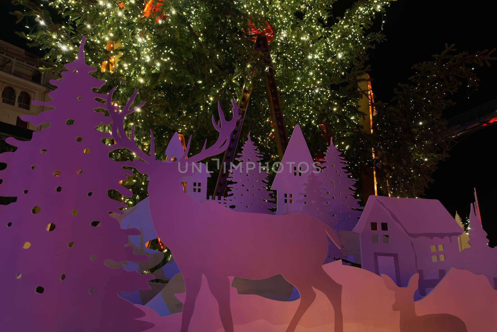 Night view of nativity scene figures around illuminated festive instalments at main city square.