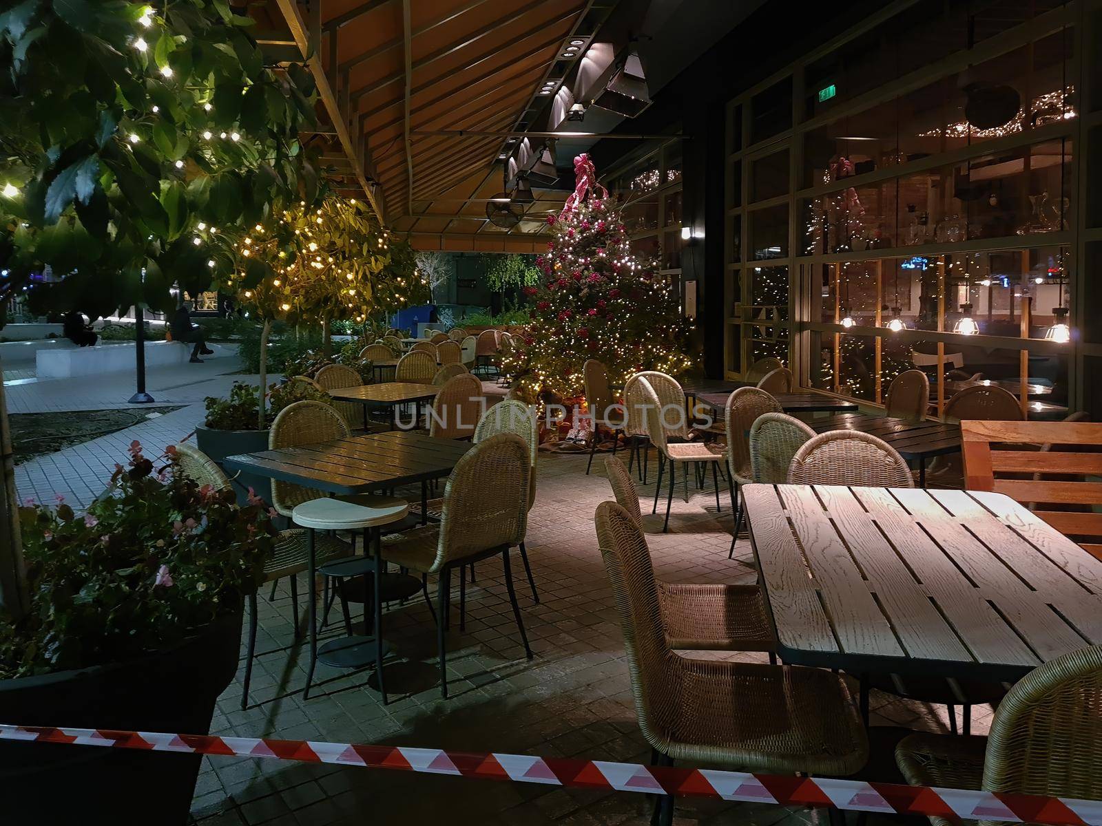 Bar at night without crowd and no access ribbon at outdoor seating area closed due to covid-19 measures.