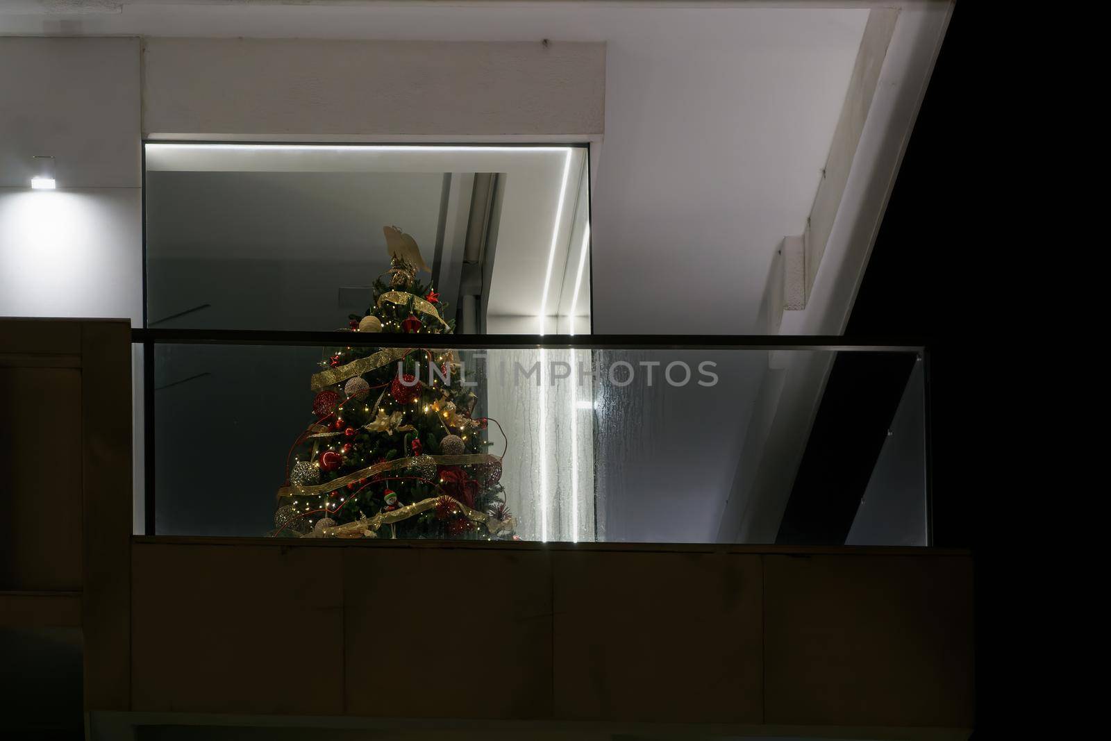 Night view of festive tree instalment with hanging seasonal ribbons, lights and balls in Thessaloniki, Greece.
