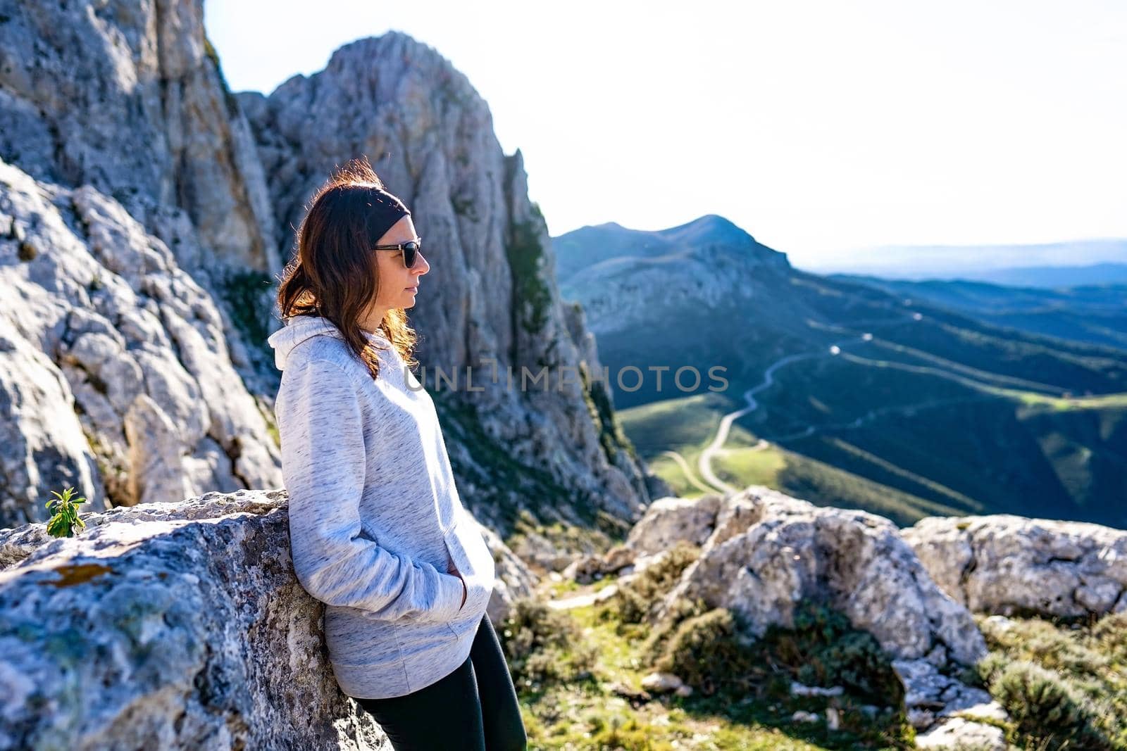 Selective focus of Caucasian young woman standing on a mountain peak with a look into the void with gorgeous panorama in background and backlight effect - Living mother nature alone to find yourself