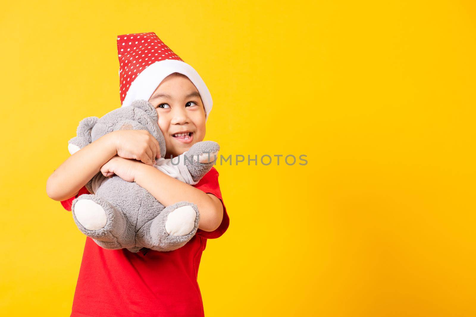 little boy smiling hugging teddy bear, Kid dressed in Santa Claus hat by Sorapop