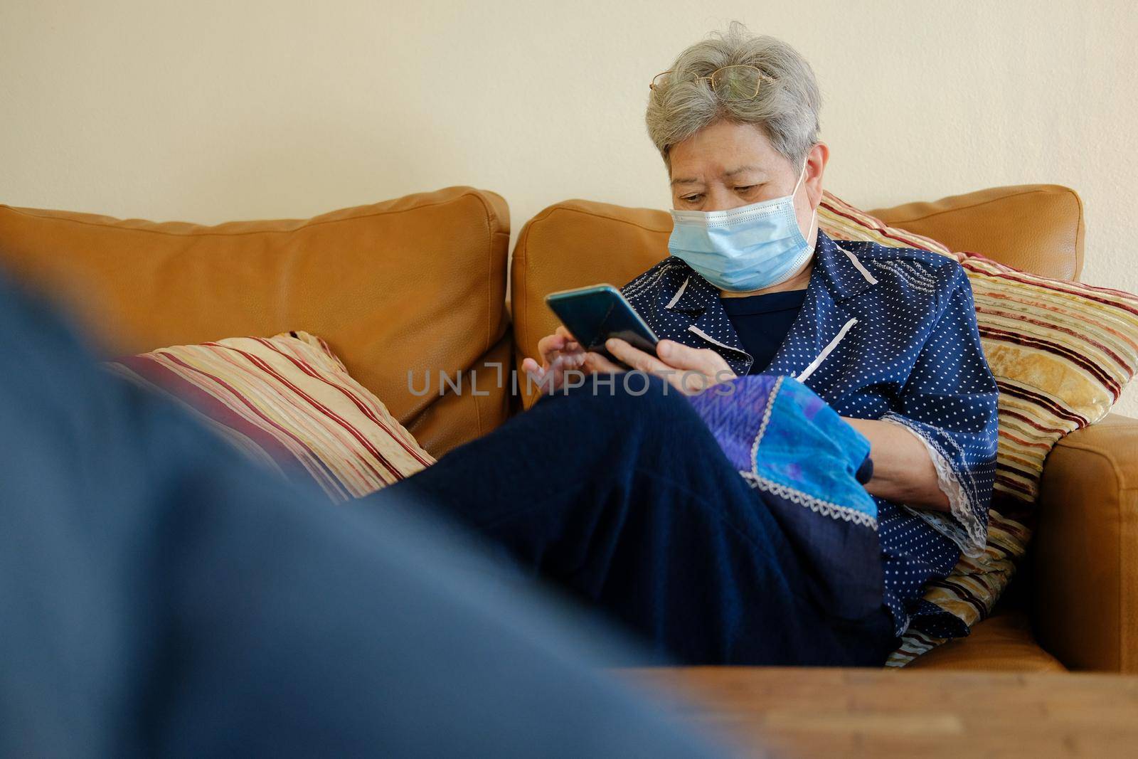 asian elder senior woman elderly wearing facial mask using mobile smart phone cellphone. mature retirement lifestyle