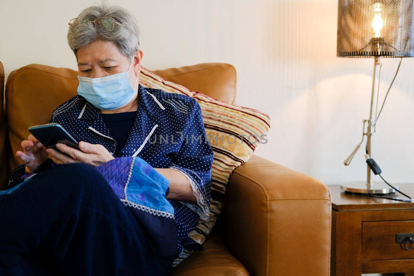 asian elder senior woman elderly wearing facial mask using mobile smart phone cellphone. mature retirement lifestyle