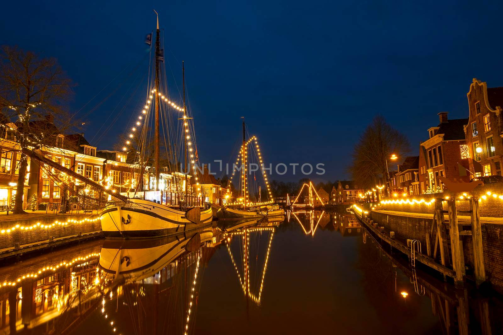 Decorated traditional boats in the harbor from Dokkum in the Netherlands at christmas at night