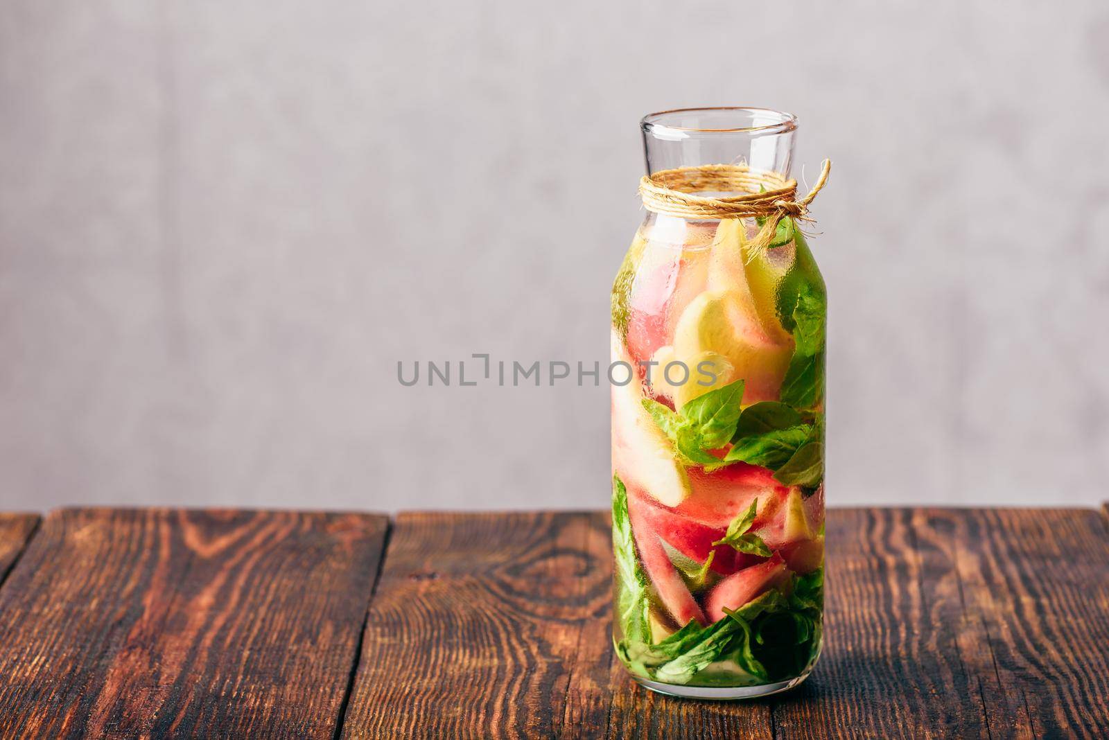 Bottle of Water Infused with Sliced Peach and Basil Leaves.