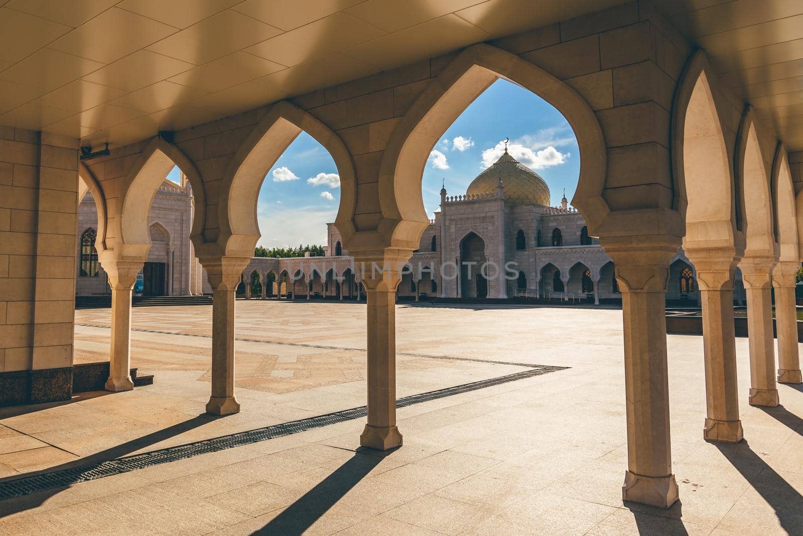 View of the white mosque in the sunset light through the Arches. Bolghar, Russia