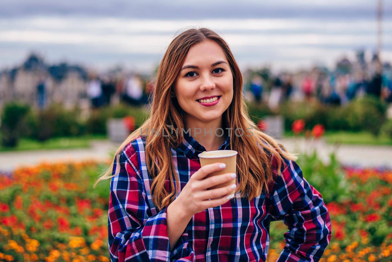 Coffee on the go. Beautiful young woman holding coffee cup and smiling in the park