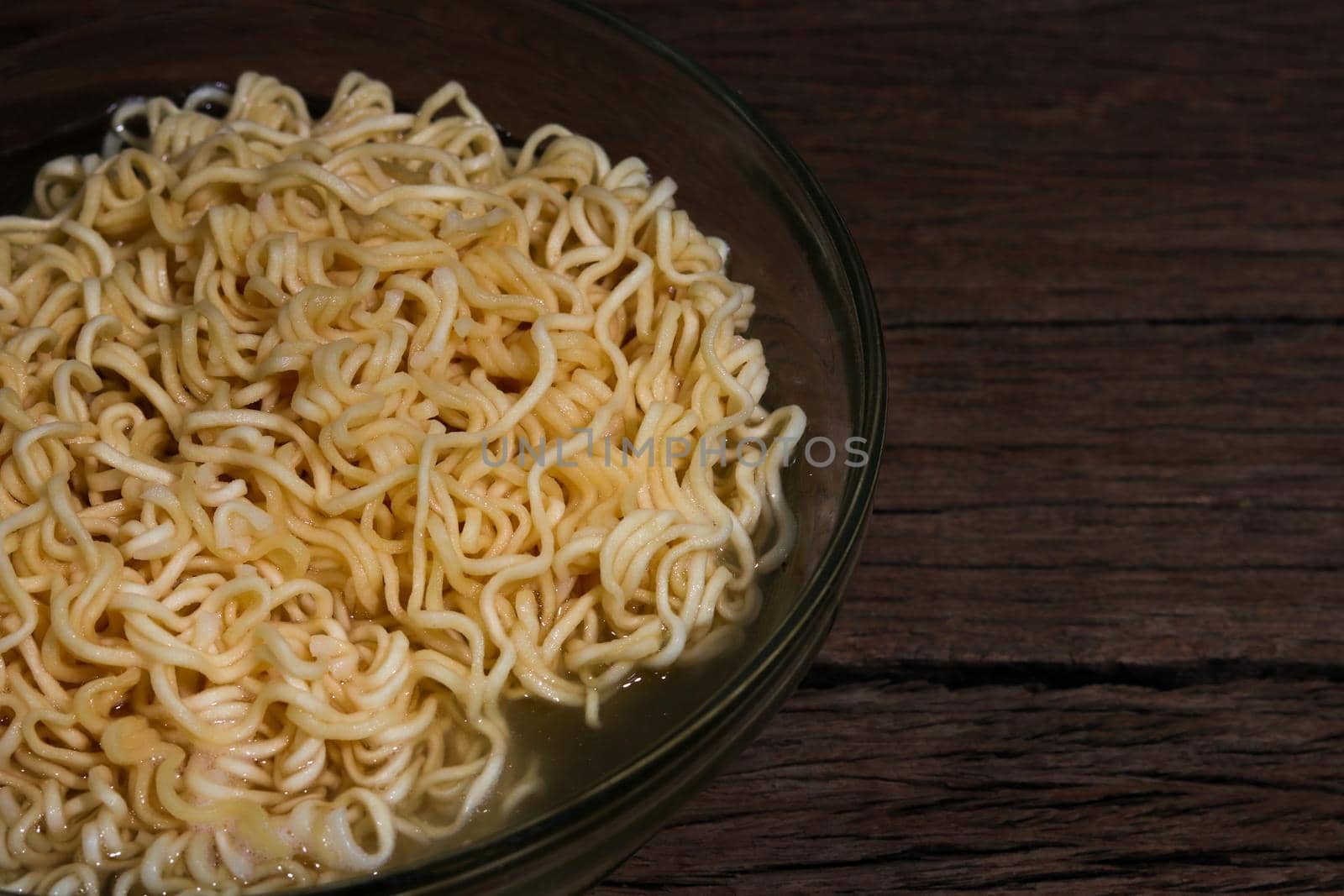 Instant noodles in bowl on wooden background.