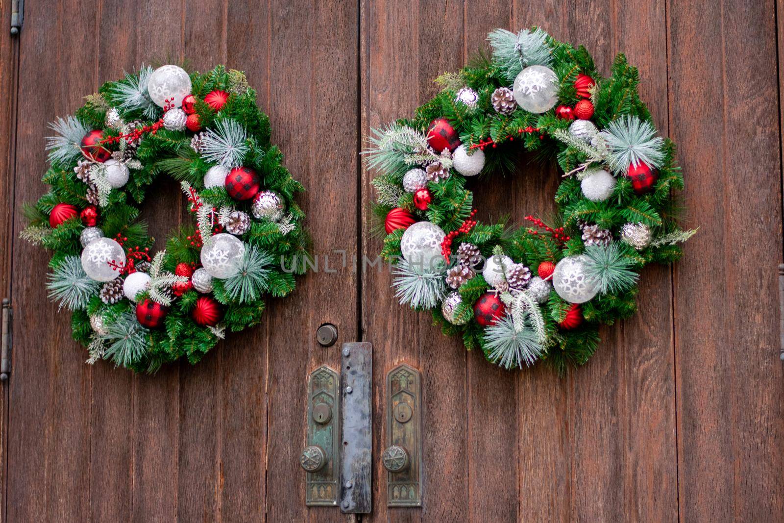 A Large Brown Wooden Door on a Church With Christmas Wreaths On Them