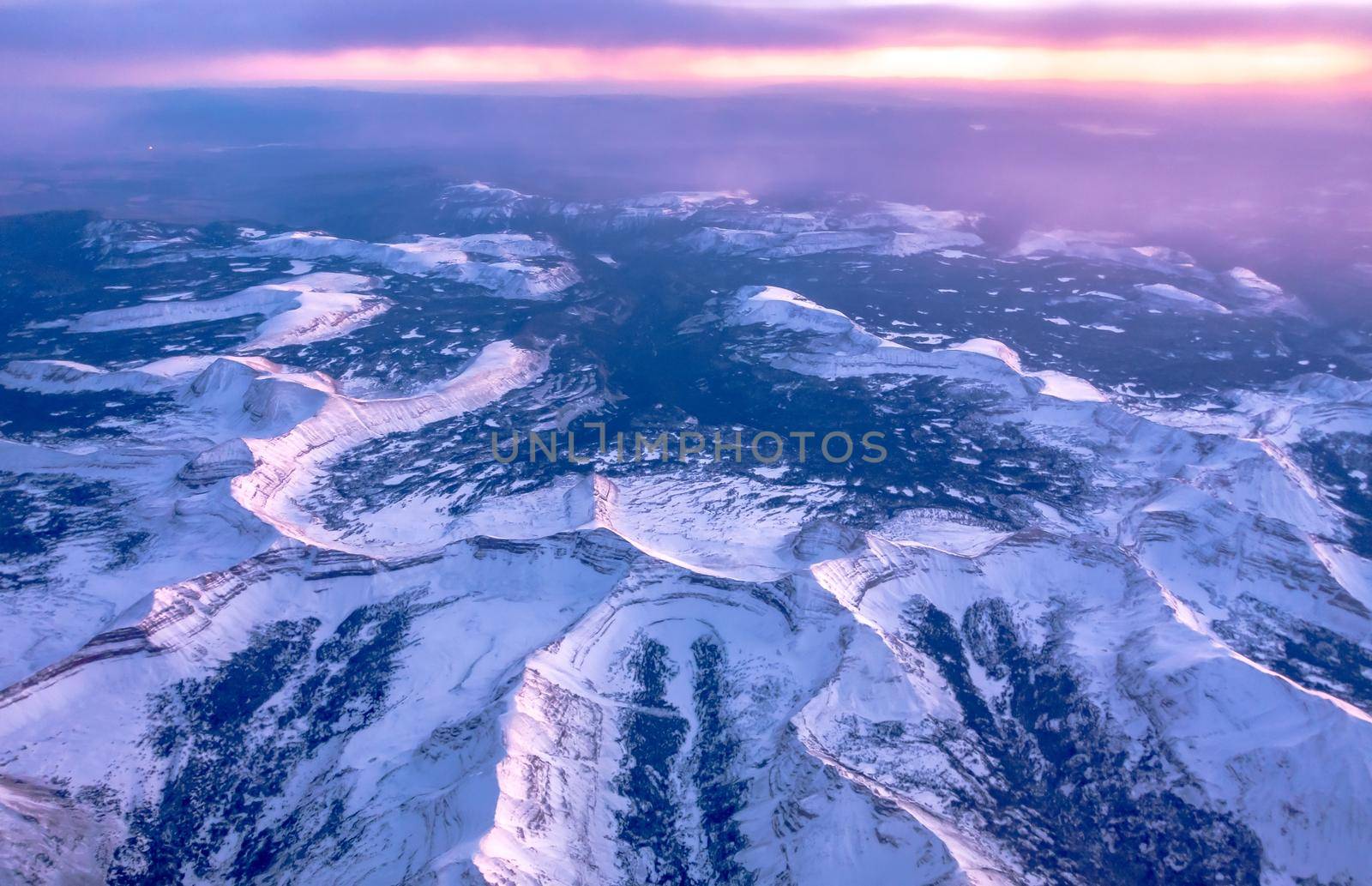 flying over rockies in airplane from salt lake city at sunset by digidreamgrafix