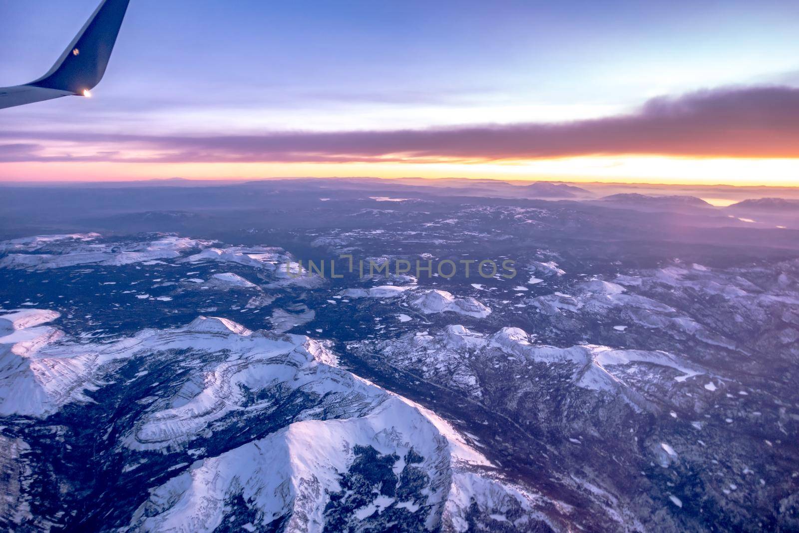 flying over rockies in airplane from salt lake city at sunset