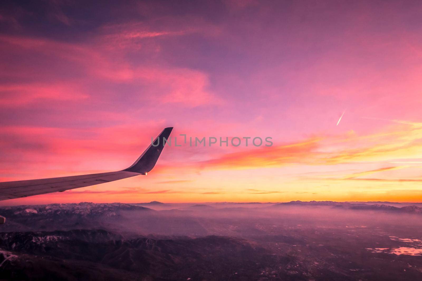 flying over rockies in airplane from salt lake city at sunset by digidreamgrafix