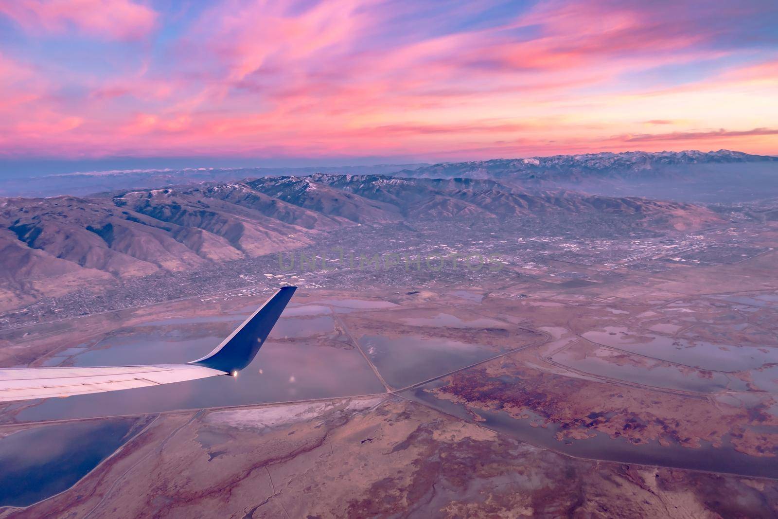 flying over rockies in airplane from salt lake city at sunset by digidreamgrafix