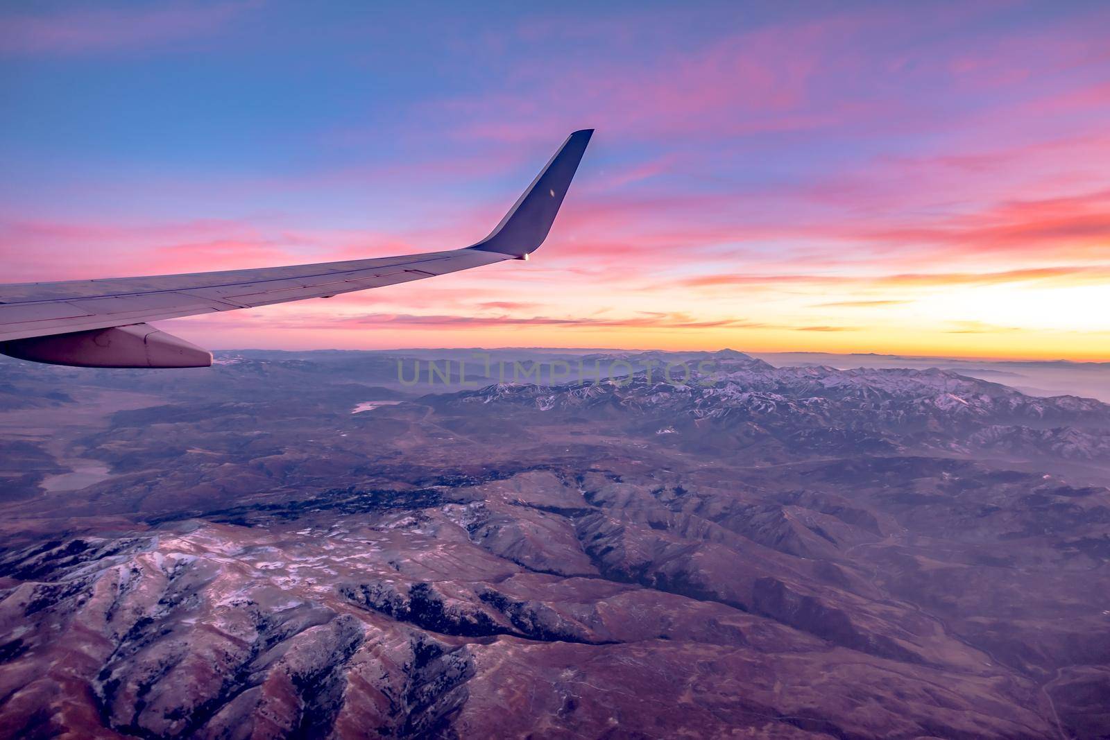 flying over rockies in airplane from salt lake city at sunset by digidreamgrafix