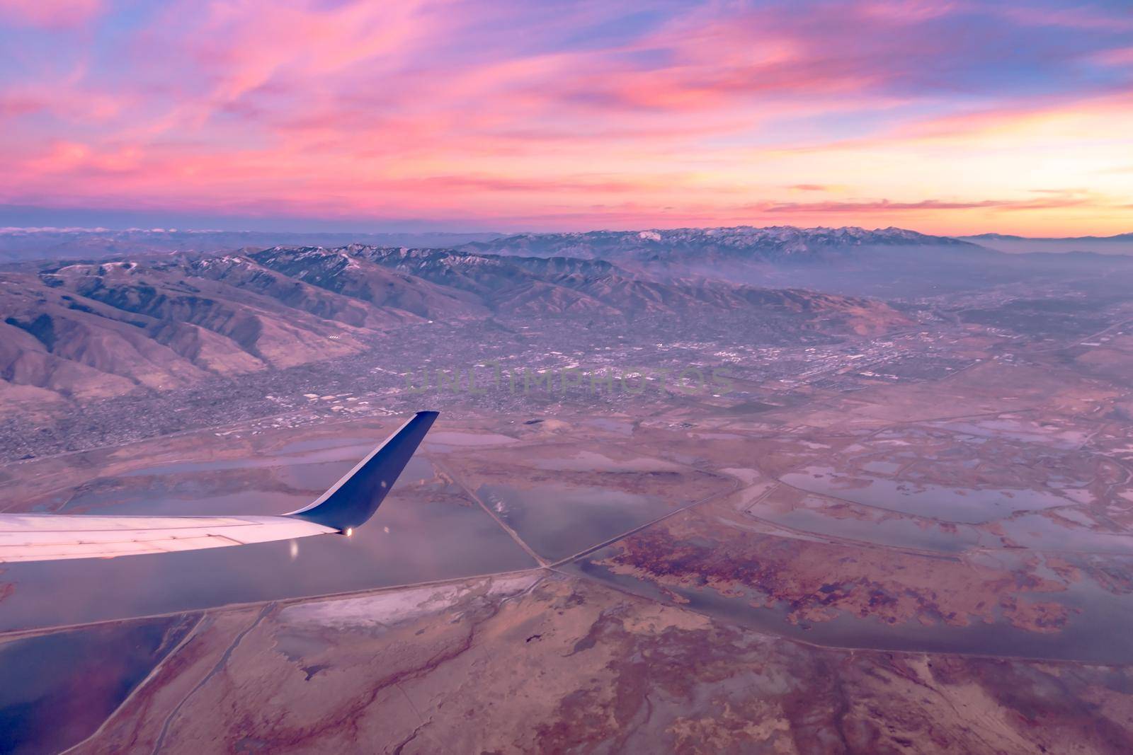 flying over rockies in airplane from salt lake city at sunset by digidreamgrafix