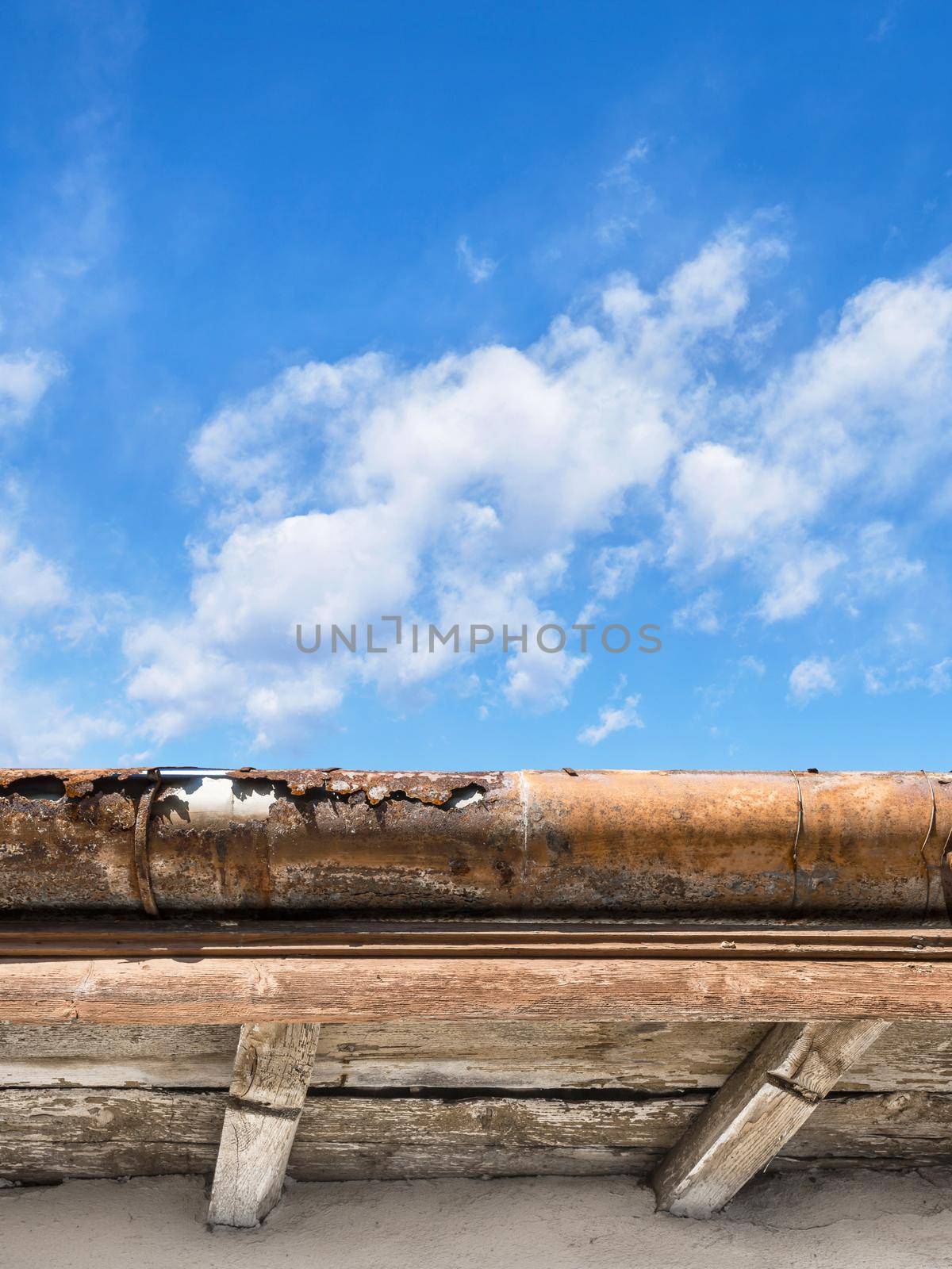 Rusted gutter. Broken gutter on an old roof. Blue sky for copy space on background.