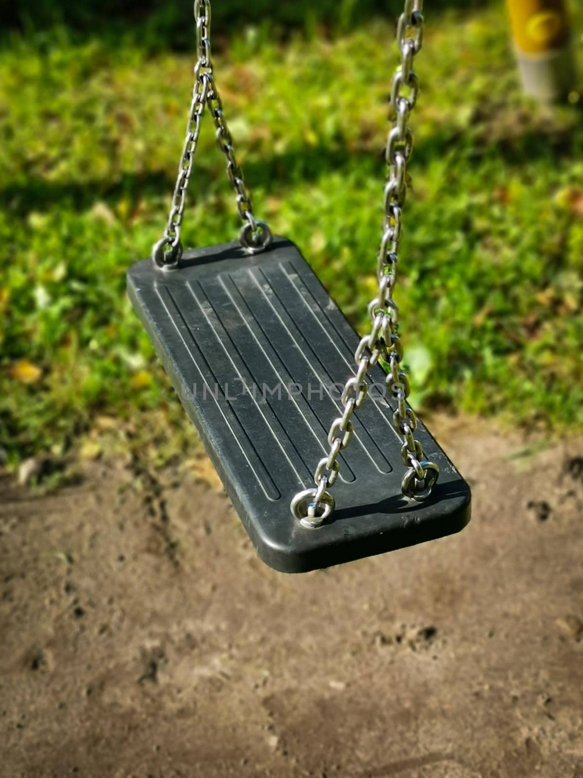 Closeup vertical shot of an empty chain swing detail in a playground