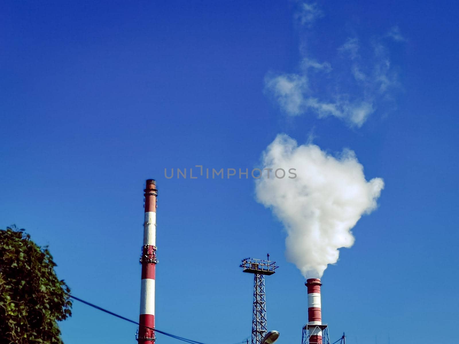 Clear sky over industrial plant pipes with smoking pipes