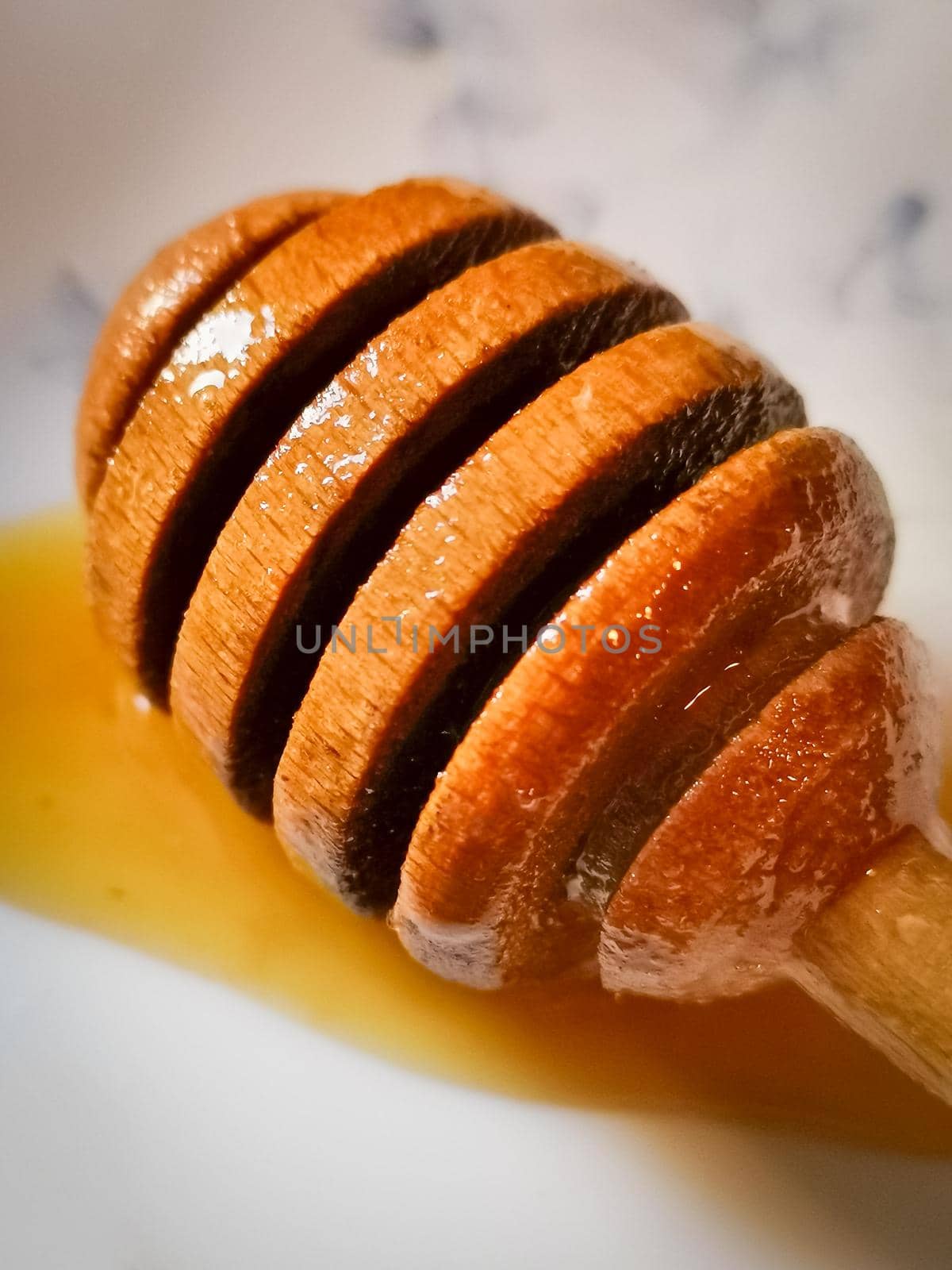 Closeup vertical shot of a wooden honey dipper on a table