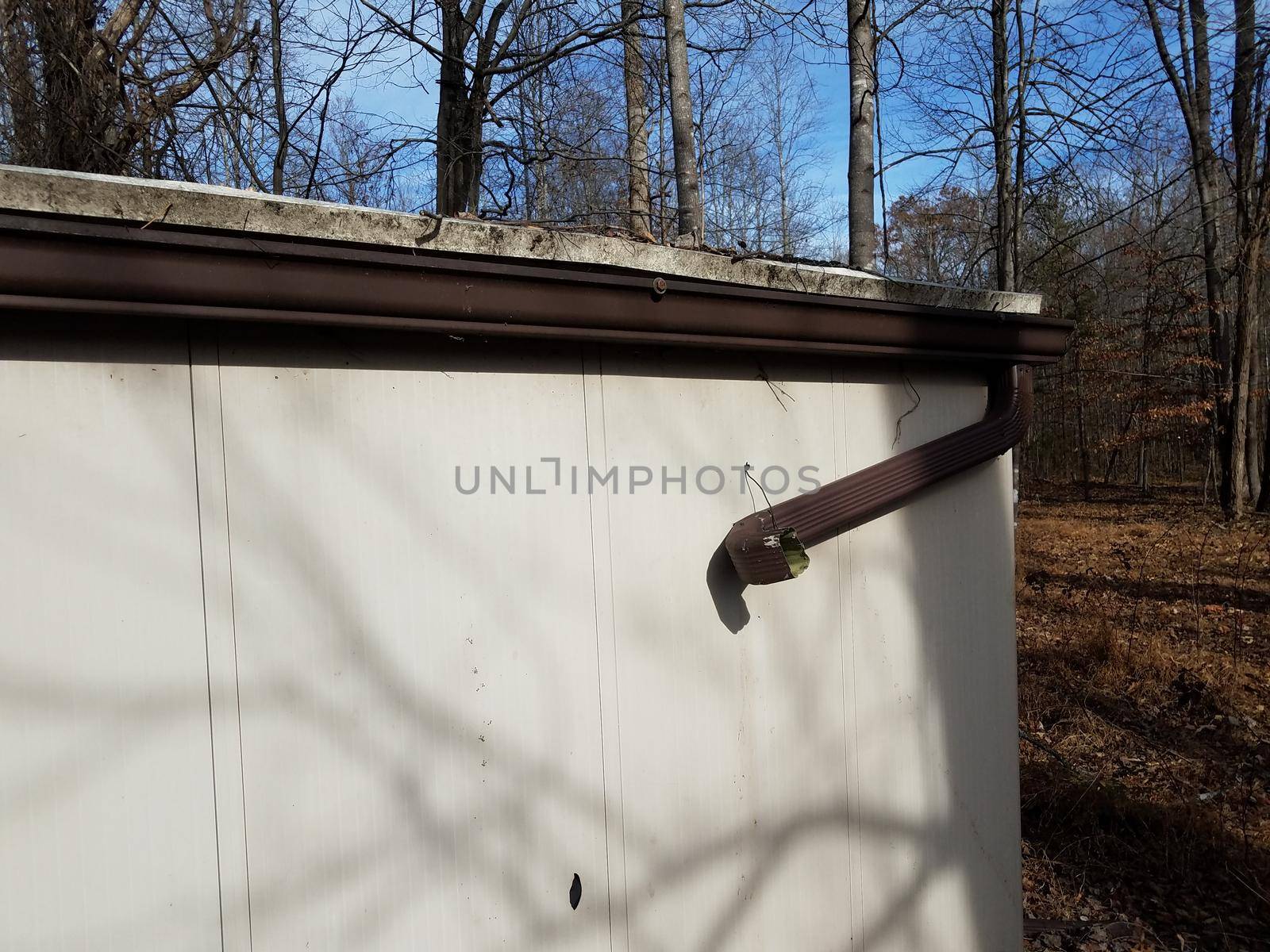 broken gutter downspout on shed in forest or woods by stockphotofan1