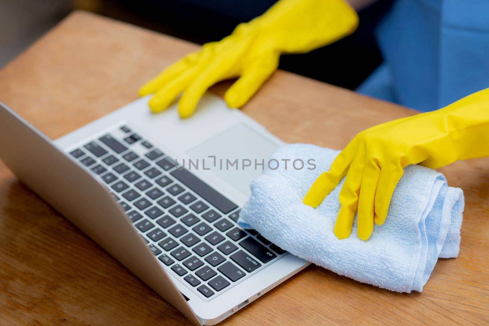 Hand of young asian woman cleaning and wipe laptop computer with disinfect and alcohol for protect pandemic covid-19 at home, girl in gloves cleaner notebook for hygiene, health care concept.