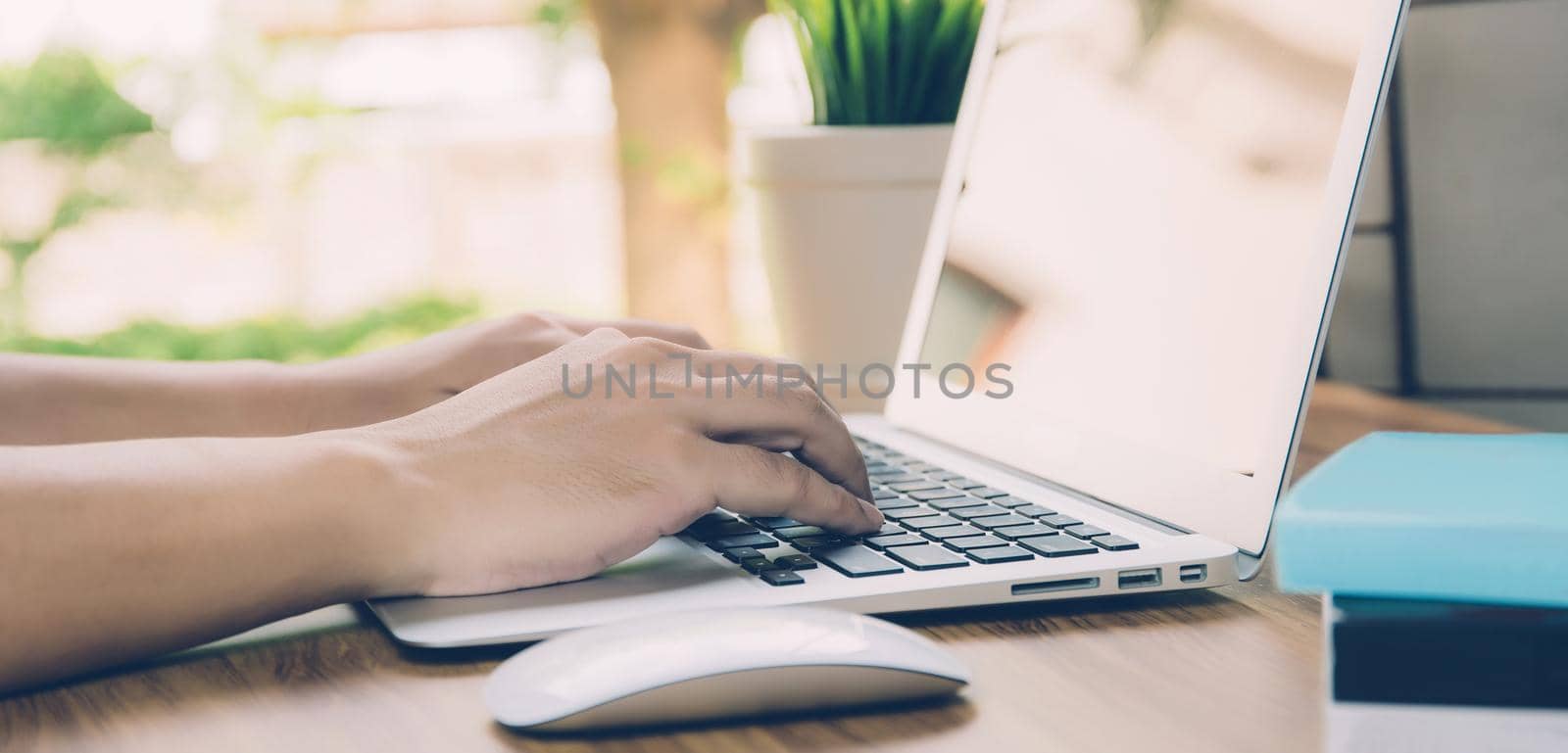 Hand of business man working from home using laptop computer on desk, lifestyle of new normal, social distancing, freelance work in stay home, employee using notebook indoor, banner website. by nnudoo