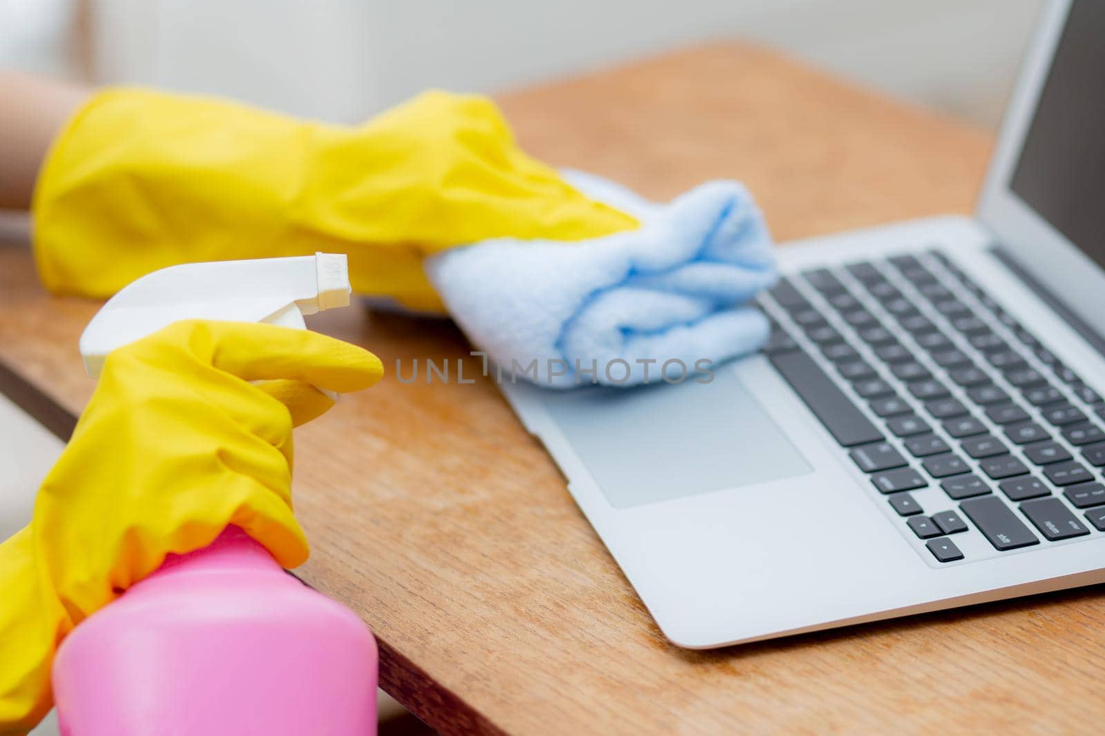 Hand of young asian woman cleaning and wipe laptop computer with disinfect and alcohol for protect pandemic covid-19 at home, girl in gloves cleaner notebook for hygiene, health care concept.