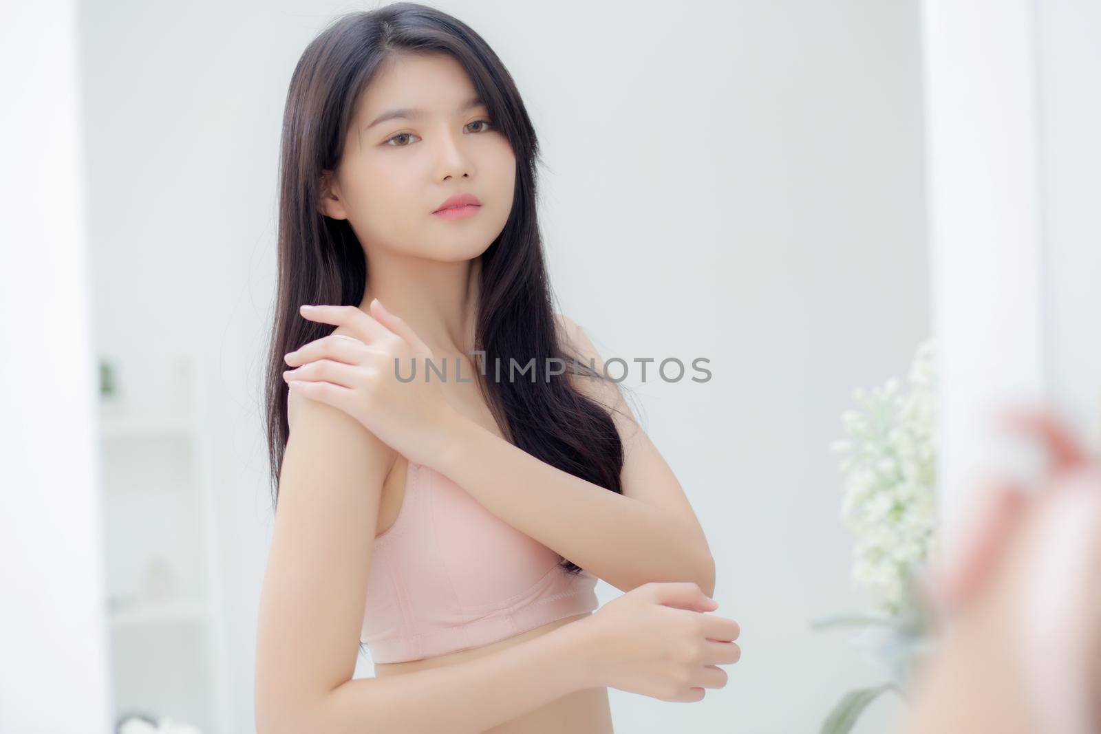 Beautiful sexy young asian woman look mirror applying cream on shoulder and message, beauty girl applying body lotion skin care for health and soft hydration, treatment and cosmetic with moisturizer.
