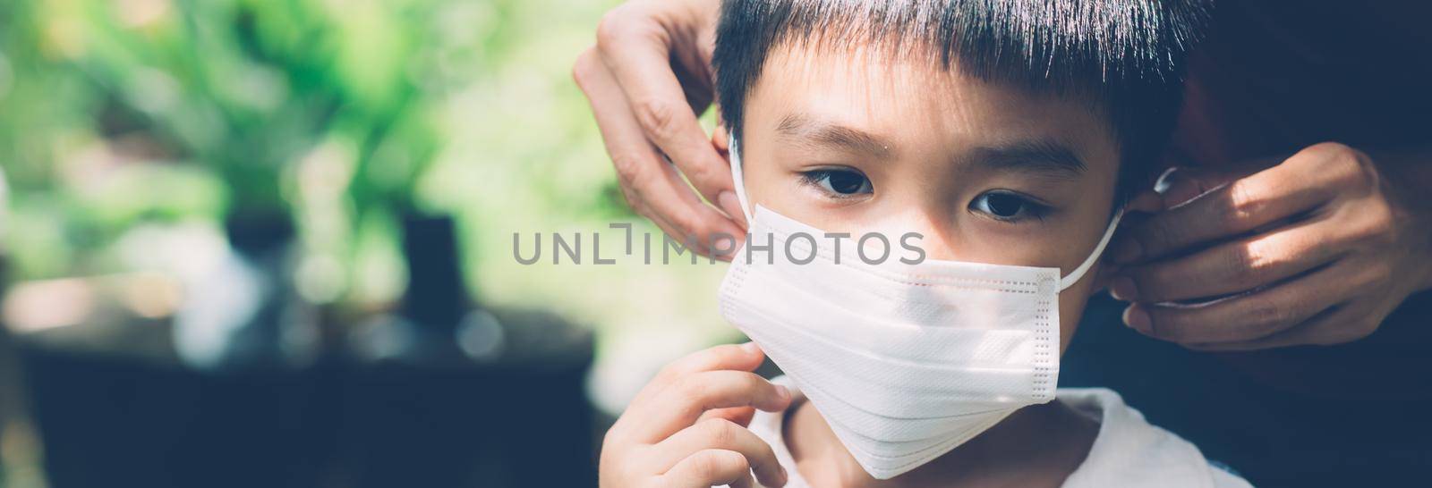 Mother take care son with face mask for protection disease flu or covid-19 outdoors, mom wearing on medical mask with child safety for protect outbreak of pandemic, medical concept, banner website. by nnudoo