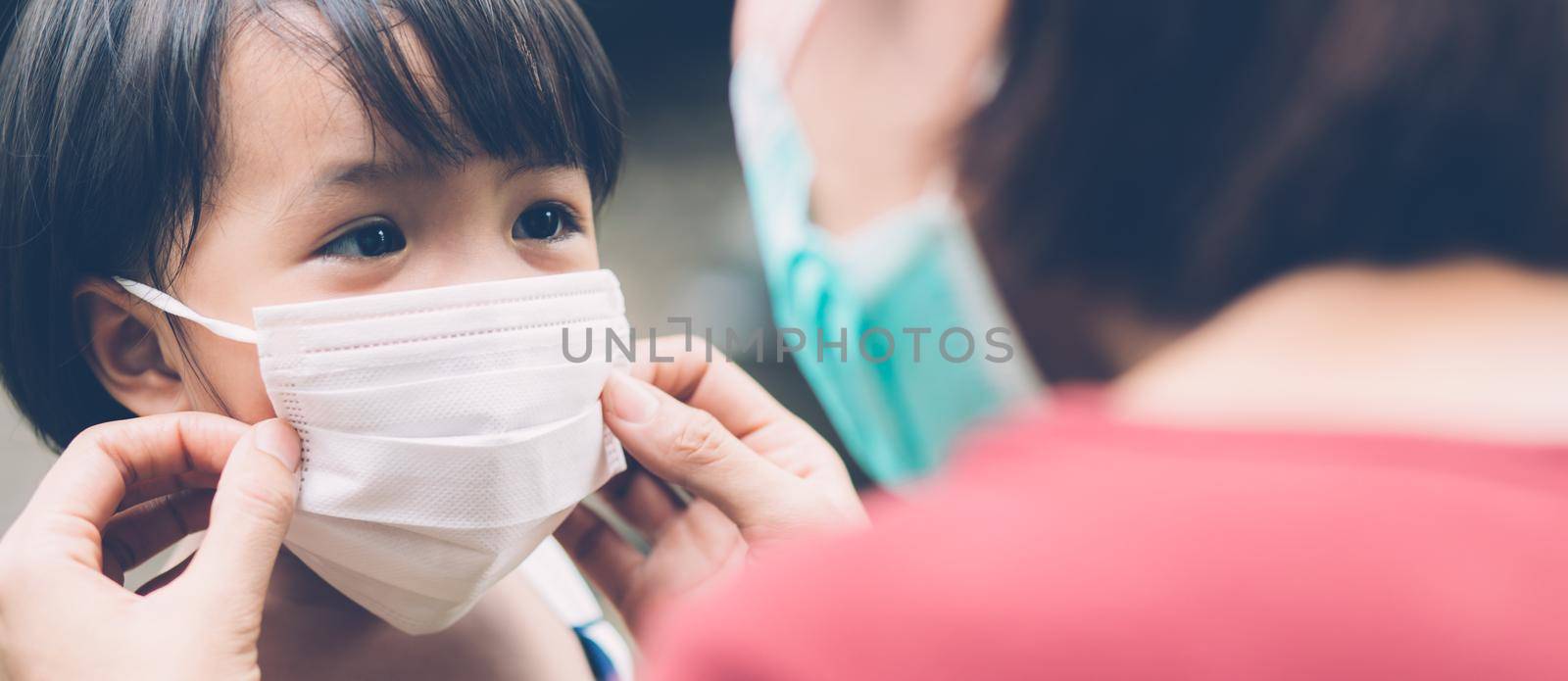 Mother take care daughter with face mask for protection disease flu or covid-19 outdoors, mom wearing on medical mask with child safety for protect outbreak of pandemic, banner website.