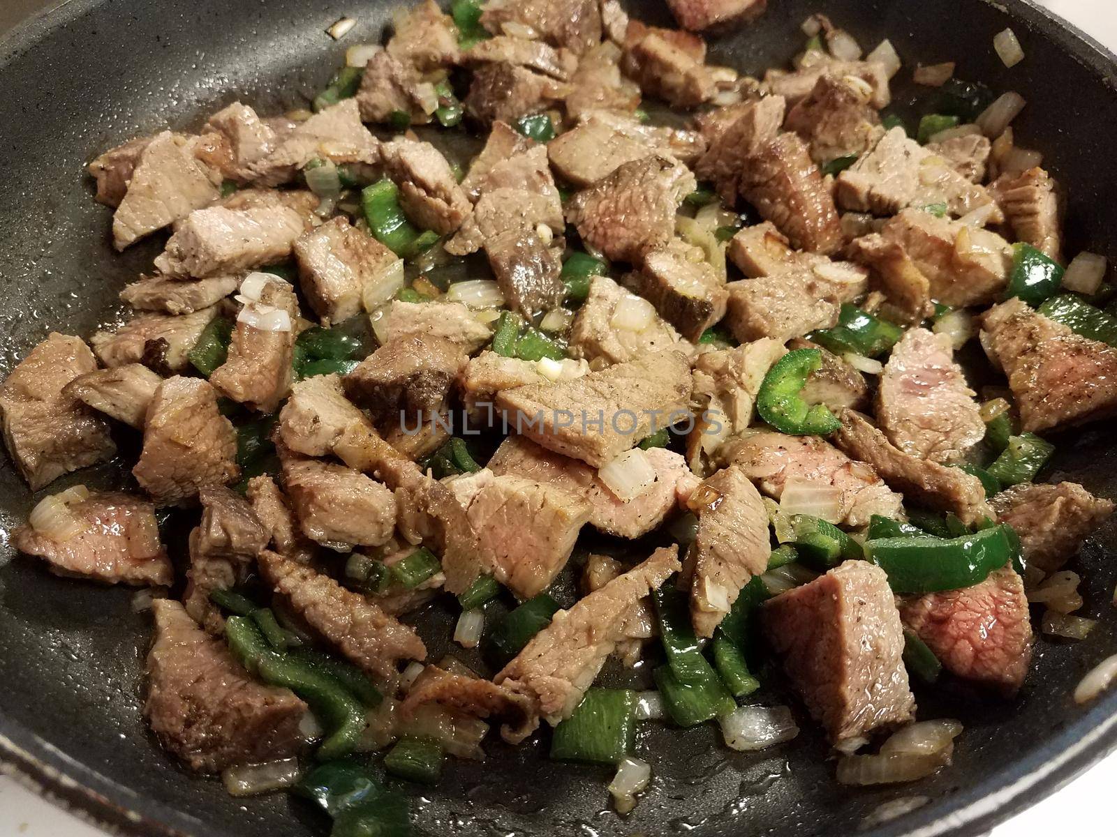 beef and hot green peppers and onions in frying pan