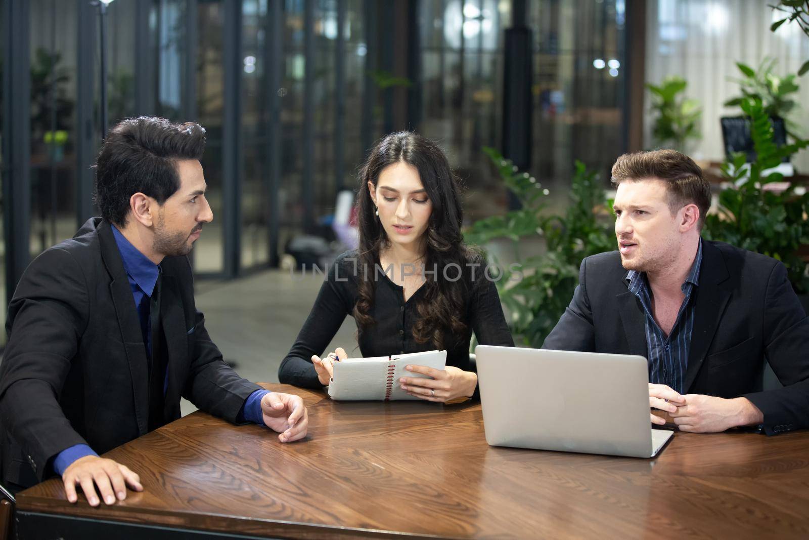 Young business team discussing and studying statistics in a meeting room by chuanchai