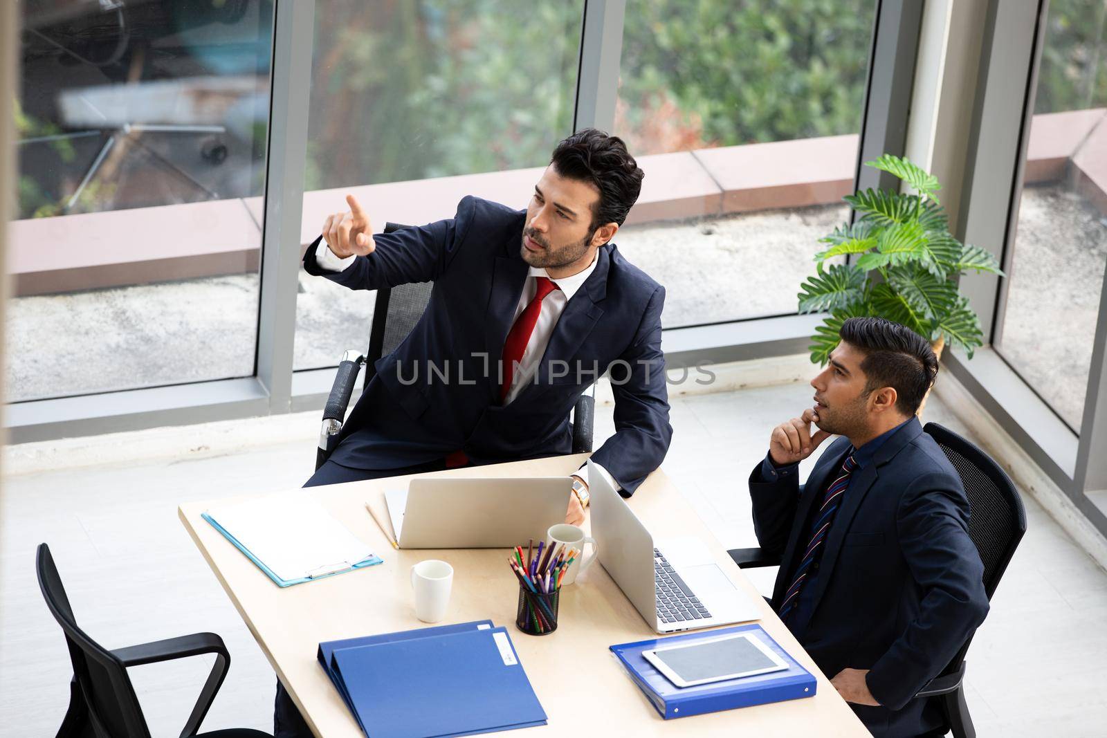 young business team working together at office. Manager pointing at a chart and explaining the analysis about business strategies. Top view shot of business hand shake