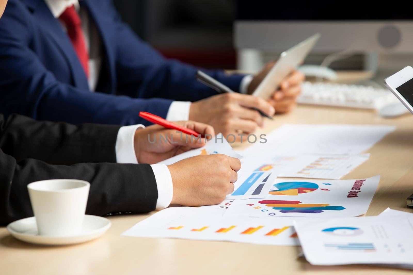 young business team working together at office. Manager pointing at a chart and explaining the analysis about business strategies. Top view shot of business hand shake