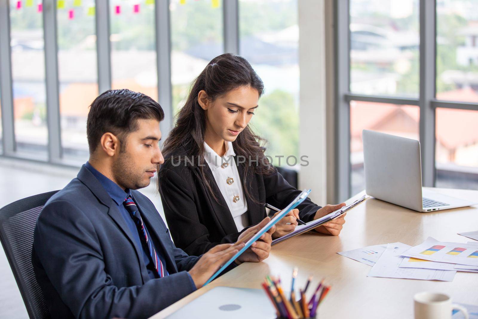 young business team working together at office. Manager pointing at a chart and explaining the analysis about business strategies. Top view shot of business hand shake