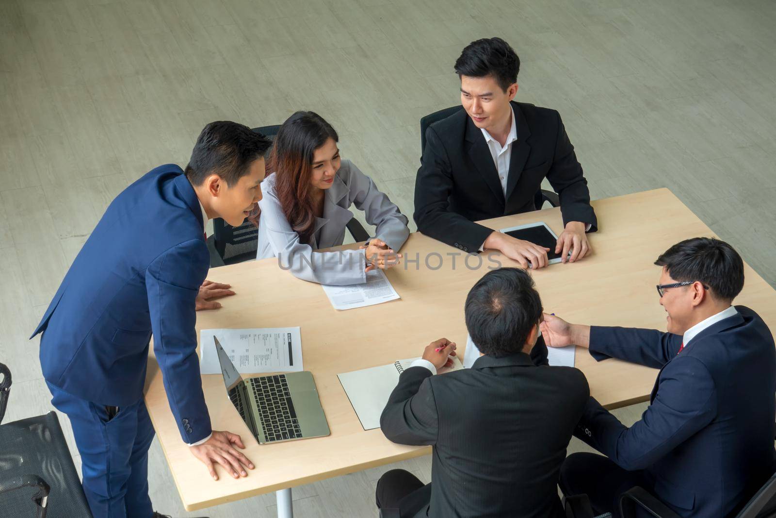 young business team working together at office. Manager pointing at a chart and explaining the analysis about business strategies. Top view shot of business hand shake