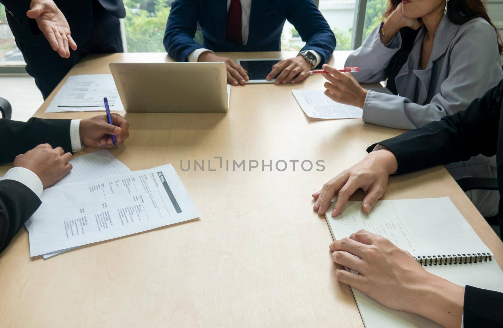 young business team working together at office. Manager pointing at a chart and explaining the analysis about business strategies. Top view shot of business hand shake