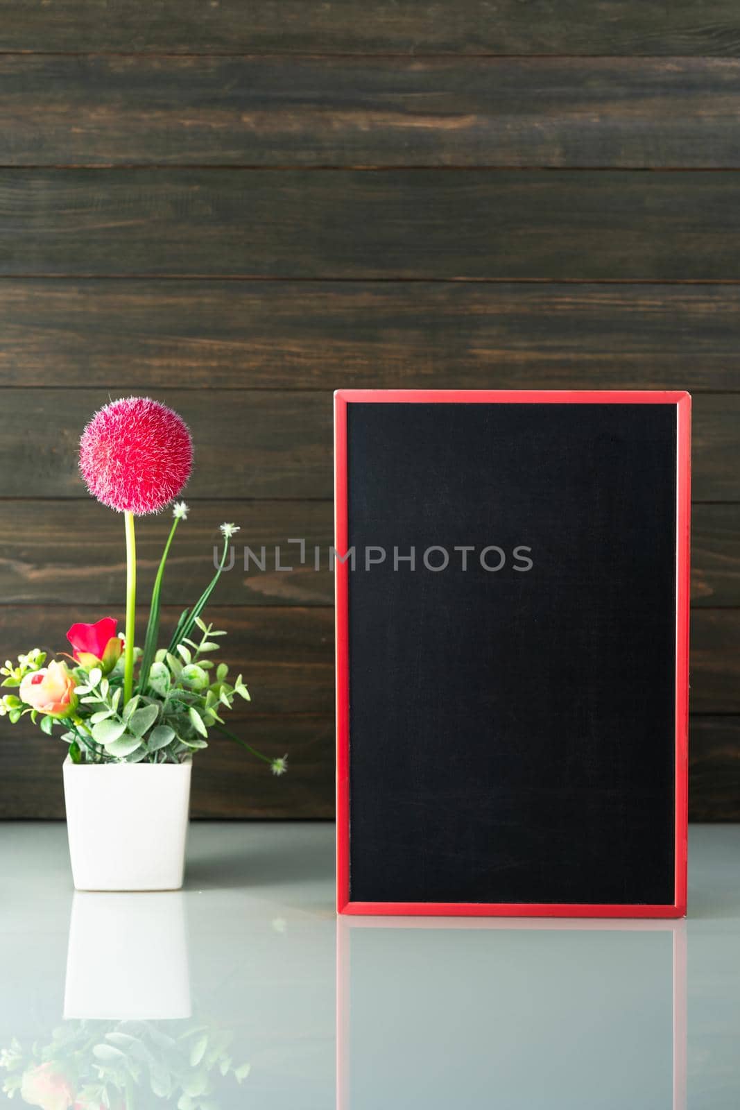 Flower vase and blank chalkboard on table near wood background