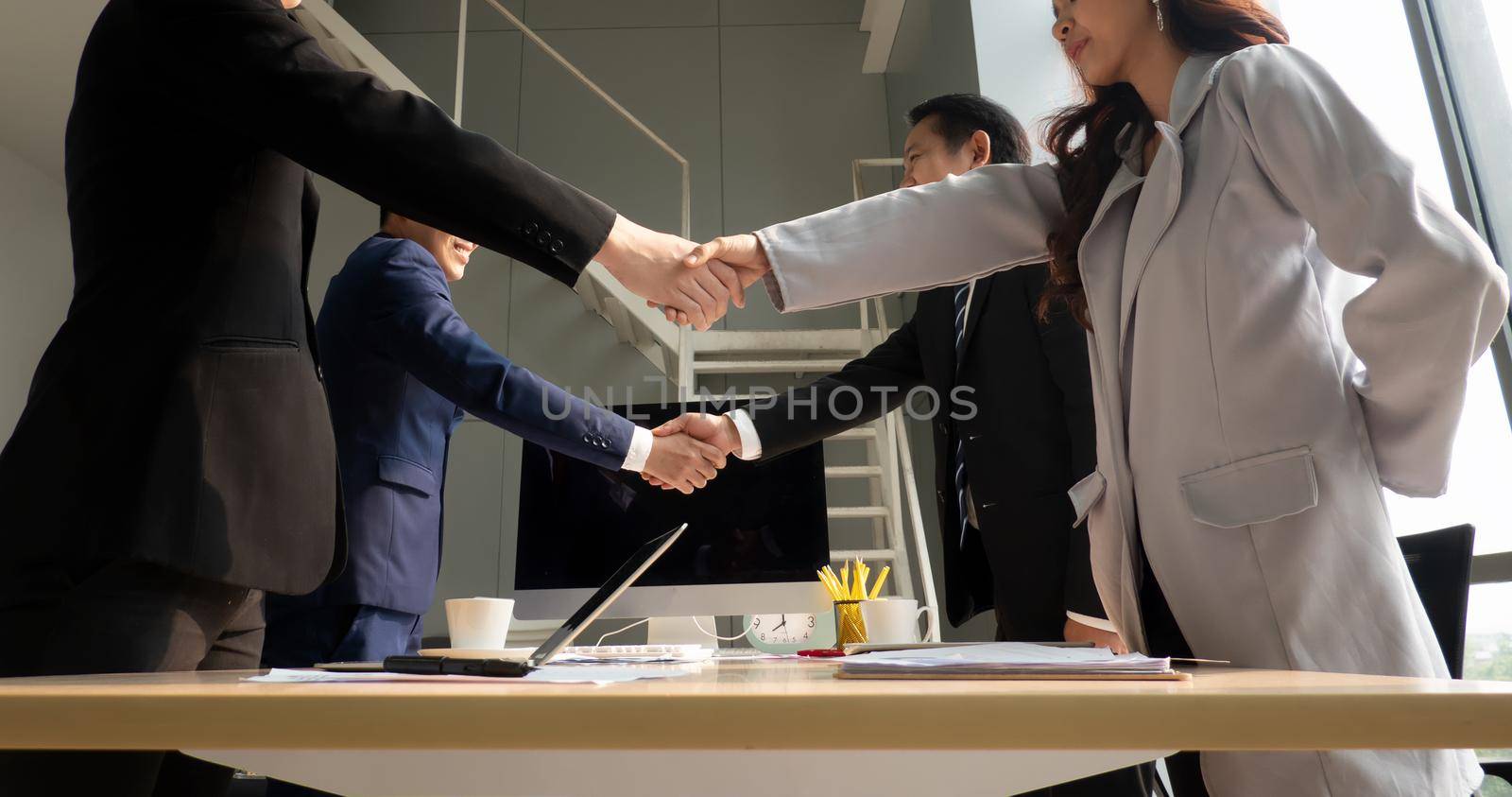 Business people shaking hands in the modern office finishing successful meeting by chuanchai