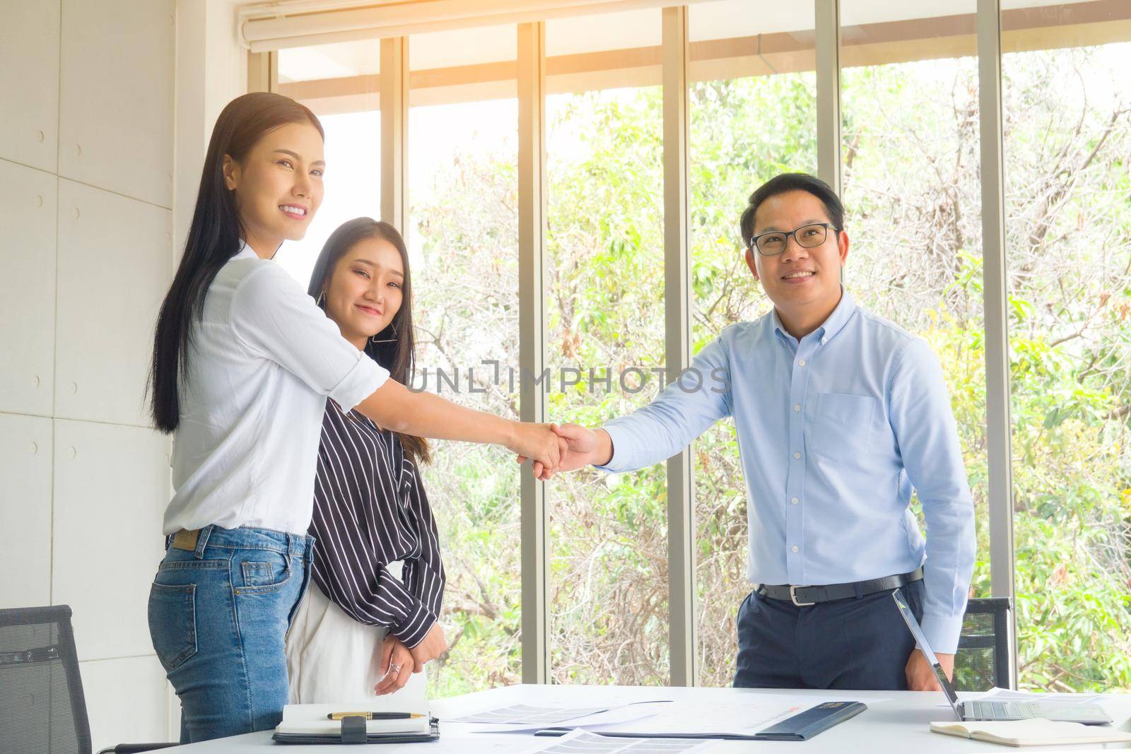 Business people shaking hands in the modern office finishing successful meeting by chuanchai