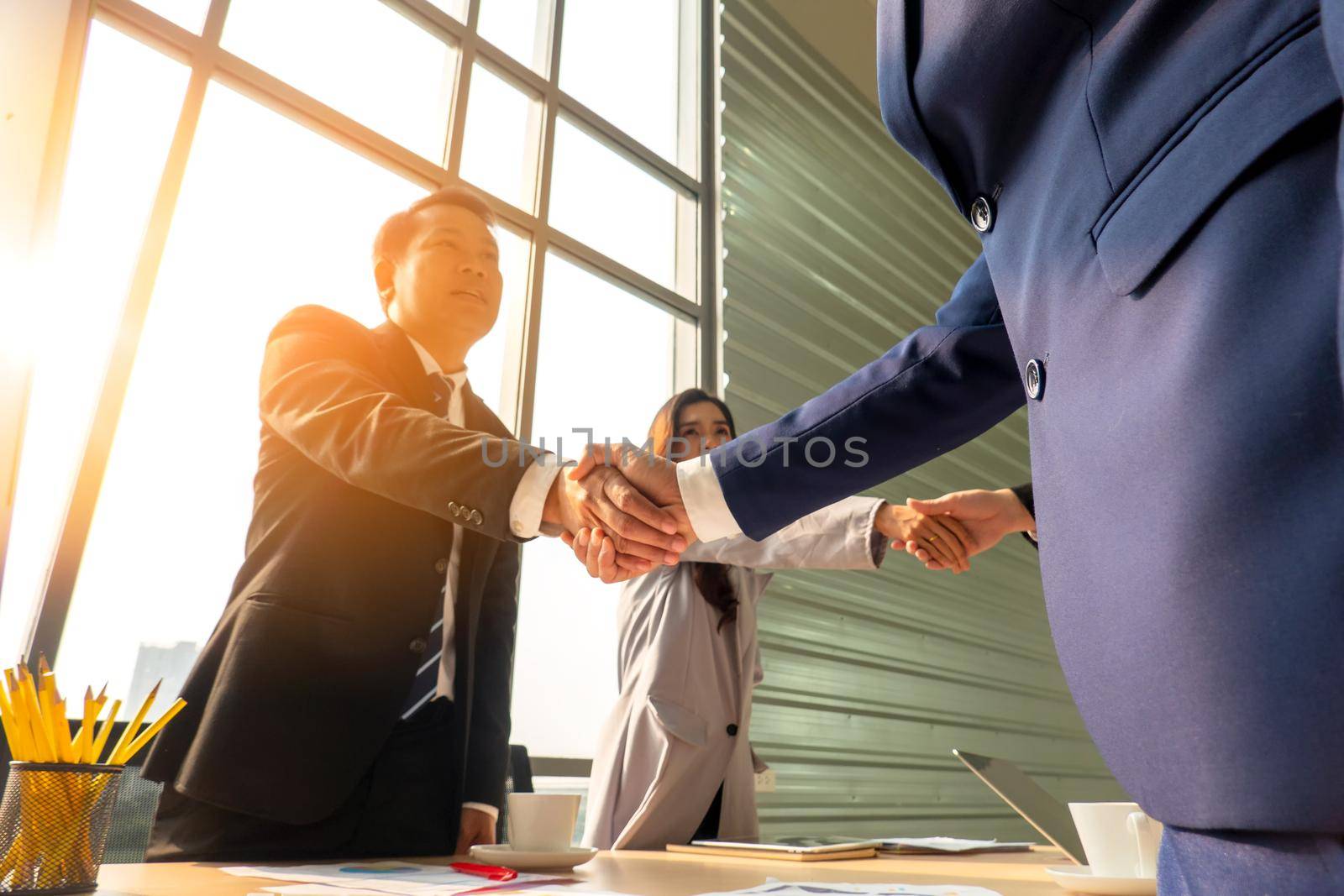 Business people shaking hands in the modern office finishing successful meeting by chuanchai
