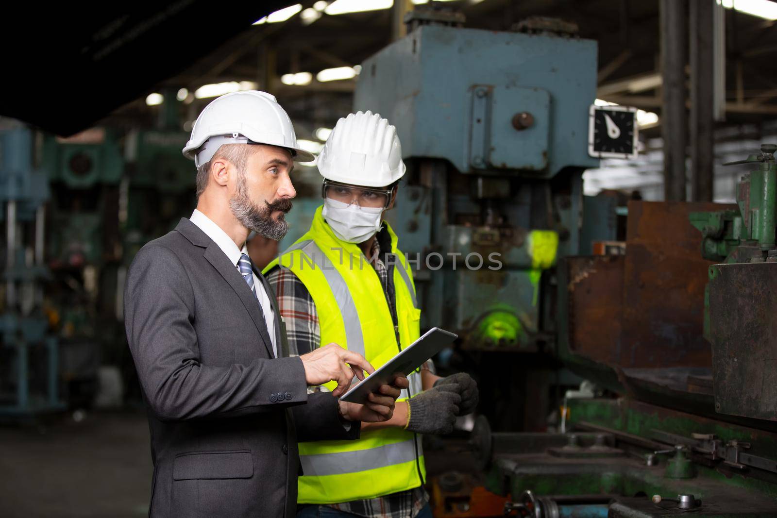 Male Industrial Engineers Talk with Factory Worker . They Work at the Heavy Industry Manufacturing Facility.