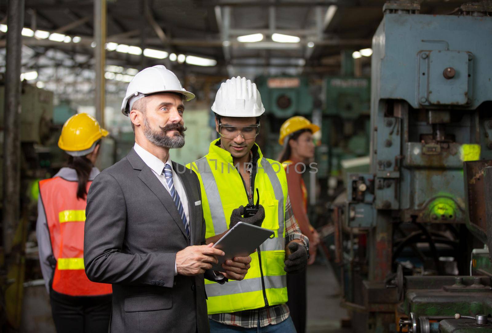 Male Industrial Engineers Talk with Factory Worker . They Work at the Heavy Industry Manufacturing Facility.