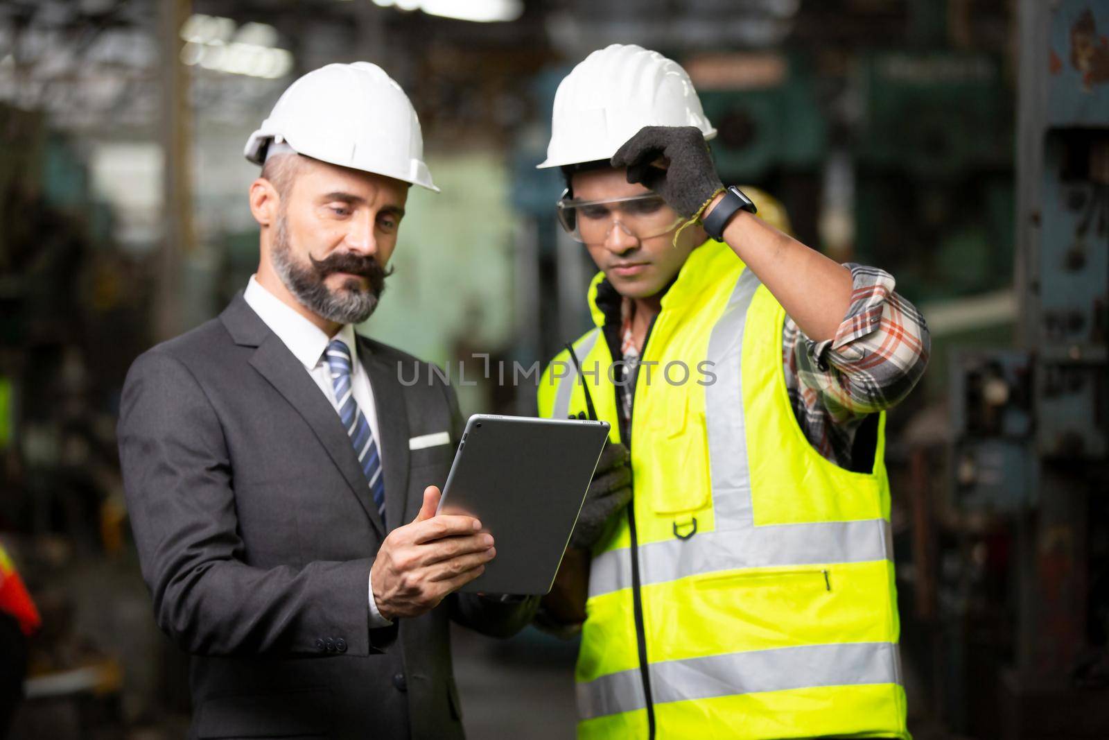 Male Industrial Engineers Talk with Factory Worker . They Work at the Heavy Industry Manufacturing Facility. by chuanchai