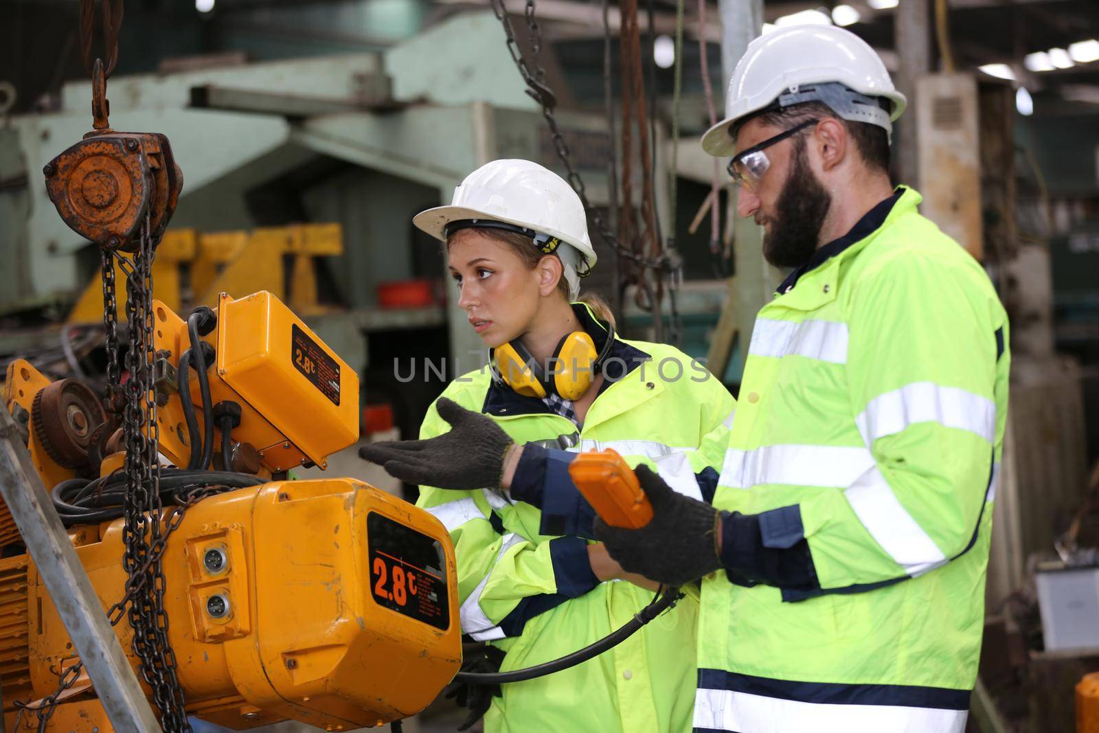 Men and female workers in factory operating machine in workshop floor.